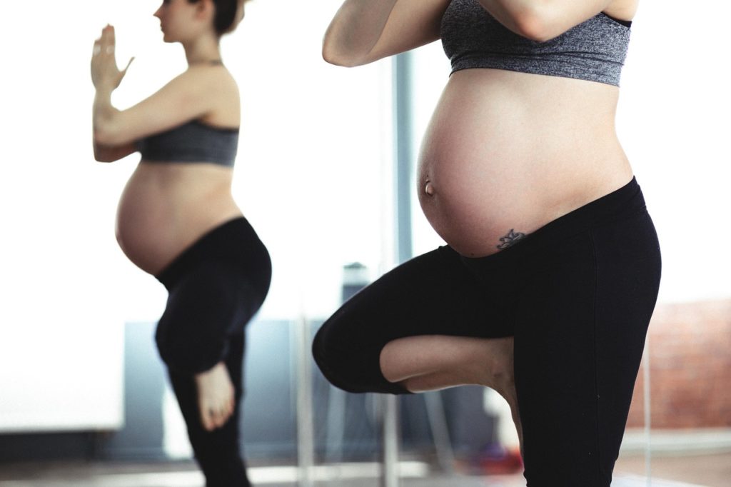 Femme enceinte en position de yoga fait du sport pendant la grossesse